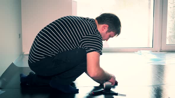 Skilled Man Taping Down Flooring Underlay with Scotch