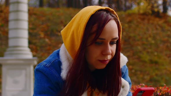 Young Woman with Mobile Phone in City Park