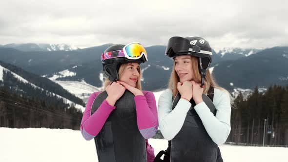 Two Stylish Women with Their Snowboards on Mountain