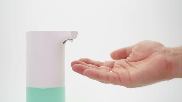 Male Hand and Automatic Dispenser, Disinfectant on an Isolated Background, Close-up. Demonstration