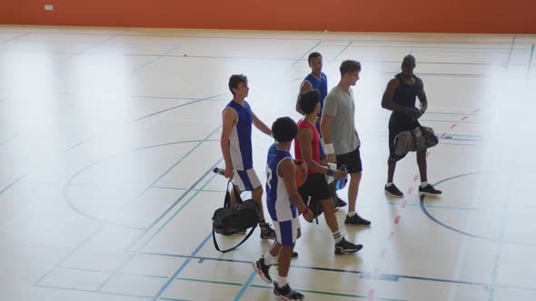 Diverse male basketball team and coach high fiving after match