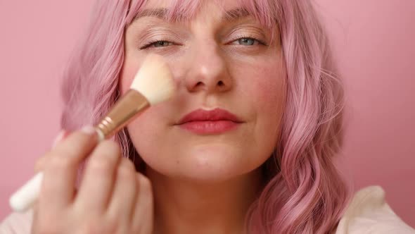 Happy Woman Smiles Holds Cosmetic Brushes for Applying Makeup Isolated Over Pink Background