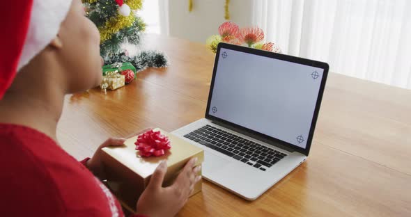 Happy african american plus size woman in santa hat, making video call using laptop at christmas