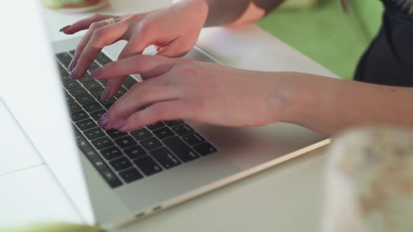 Female Hands Typing on Keyboard of Laptop on Kitchen Table