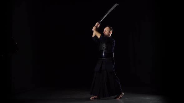 Kendo Warrior Practicing Martial Art with the Katana Sword on Black Background