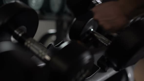 Closeup of Male Hand Taking Dumbbells, Strength Training Equipment in Gym