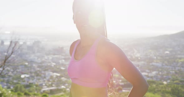 African american woman exercising outdoors wearing wireless earphones using watch in countryside