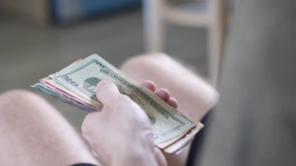 Men's Hands Count Cash Dollars and Other Currencies at Home in a Bright Room