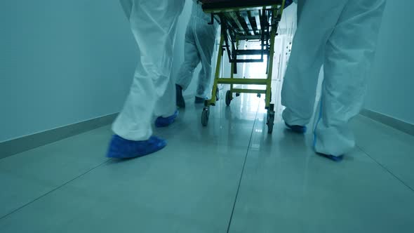 Medical Workers Transport a Man with Coronavirus on Stretcher in Hallway.