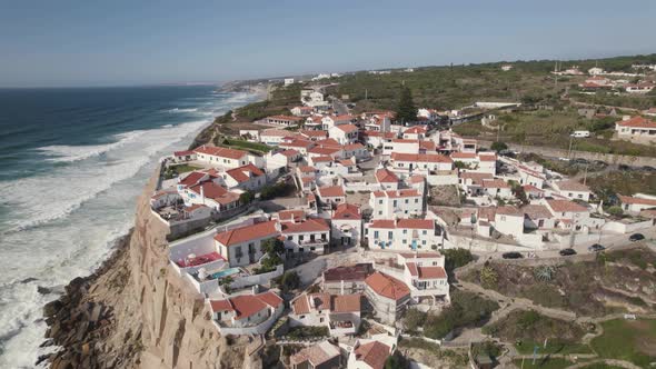 Luxury town of Azenhas Do Mar on high cliffside on majestic blue ocean, aerial orbit view