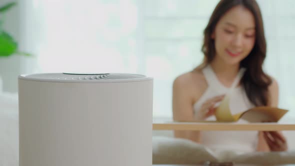 air purifier in living room for clean and fresh air with woman reading ad relax in background