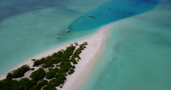 Daytime birds eye tourism shot of a sandy white paradise beach and blue sea background in vibrant