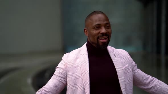 Portrait of an African Man with a Beard in a Dark Turtleneck and Light Jacket on the Background of a