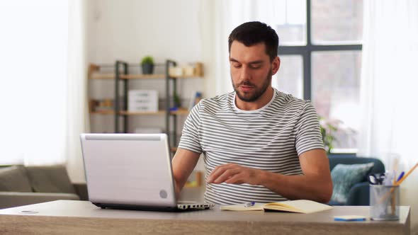 Man with Notebook and Laptop at Home Office