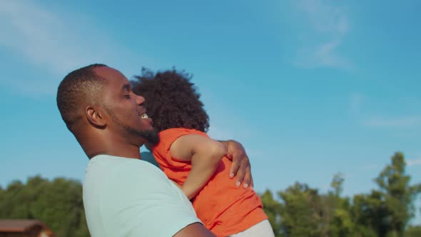 Affectionate Father Embracing Little Boy Outdoors