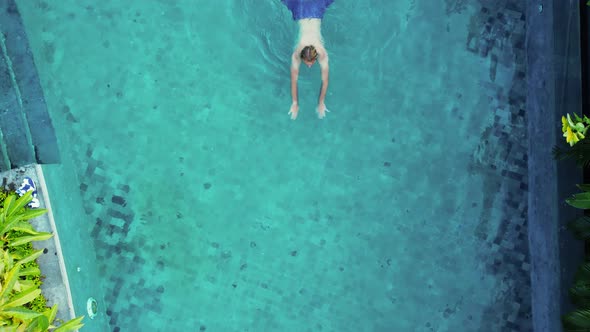 Man in Blue Trunks Swim in the Blue Water Pool