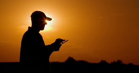 Farmer Using Digital Tablet at Farm Against Sunset