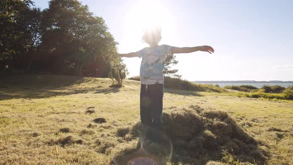 Boy Falling Into Heap Of Grass In Meadow