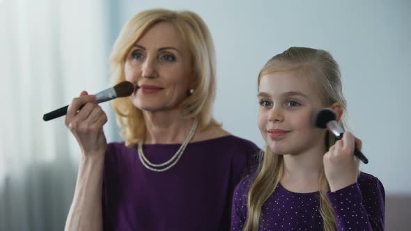 Joyful Granddaughter and Her Granny Applying Face Powder, Preparing for Party