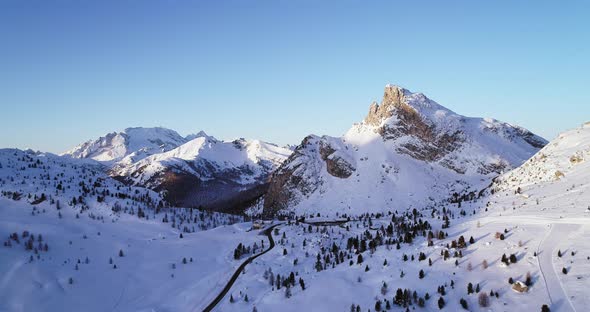 Forward Aerial to Snowy Valley with Woods Forest and Road at Falzarego Pass