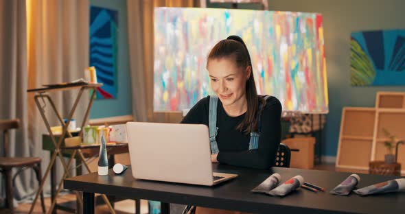 A Beautiful Young Painter Works in a Salon a Painting Studio Sits at Desk in