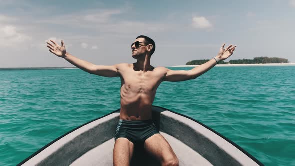 Young Successful Man with Arms Outstretched Enjoying on Deck of Boat at Ocean
