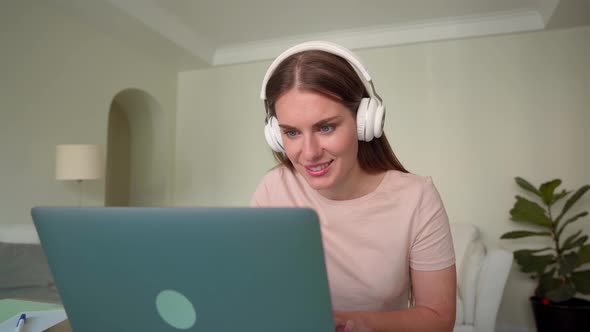 Younge Woman in Headphone Using Laptop for Playing Video Games at Home