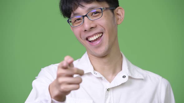 Young Asian Businessman Smiling and Pointing To Camera