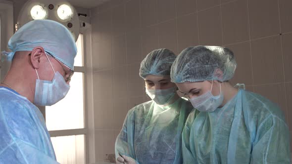 the Surgeon Explains To Nurses During an Operation in the Hospital Room