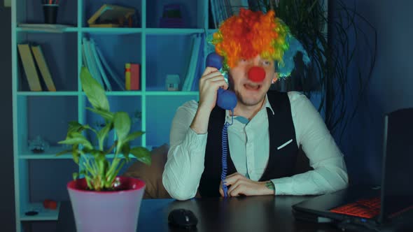 Young Man in Image of Clown Talks and Agrees on Phone in Office