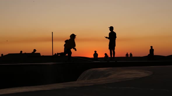 Silhouette of Young Jumping Skateboarder Riding Longboard, Summer Sunset Background. Venice Ocean