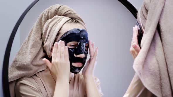 Young woman applying face mask in bathroom and smiling.