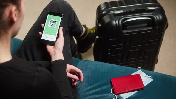 Woman Tourist Holding QR Code on Phone Sitting in Airport Terminal