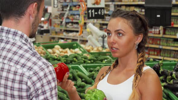 Attractive Young Woman Choosing Paprika Peppers at the Market