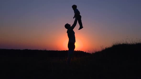 Father Throws Up Son at Sunset