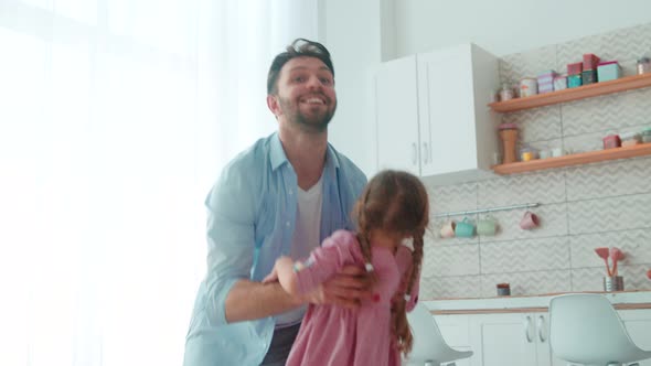 Smiling father circling little daughter in home interior
