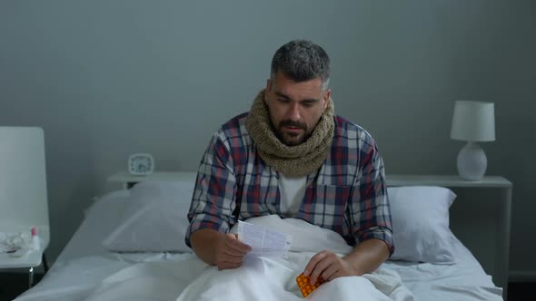 Man Reading Instruction for Antiviral Drugs Coughing Sitting in Bed, Caught Cold