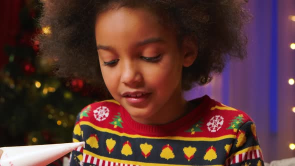 Cute Curly Haired African American Girl Enjoys Trying the Icing To Decorate the Cookies