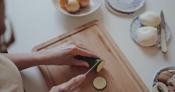 Close-up of woman cutting zucchini for homemade pizza