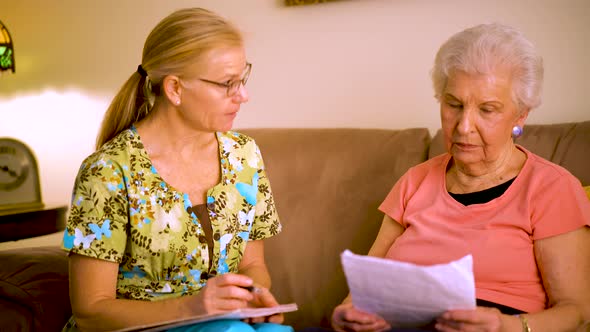 Front view closeup of elderly woman and home healthcare nurse going over paperwork.
