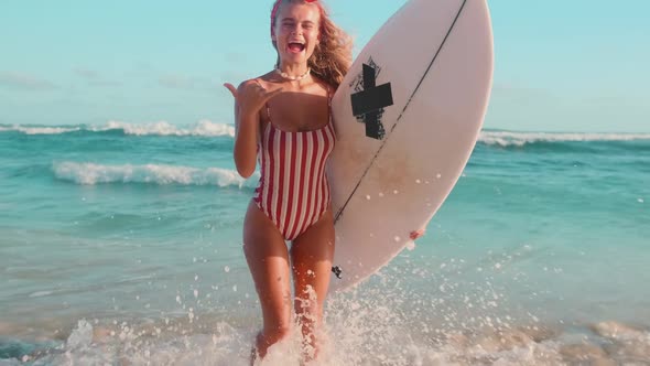 Young Cheerful Caucasian Woman with Surfer Board Showing Shaka Gesture