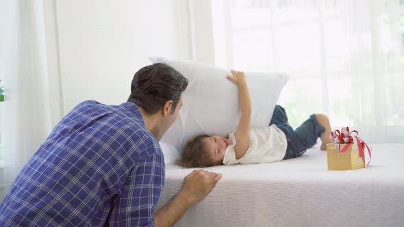 Happy family having fun in bed room concept. Smiling Dad hitting her little girl with pillow