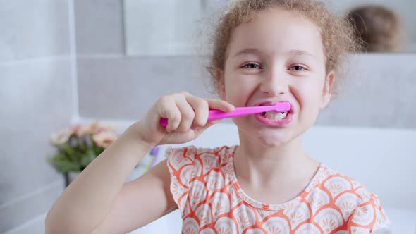 Portrait Happy Cute Young Teenage Girl Brushing Teethin the Morning in Bathroom and Smiling