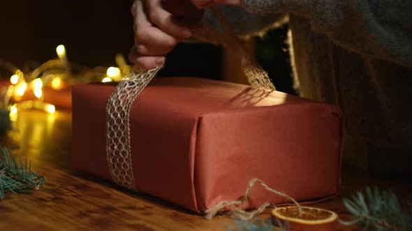 Woman Tie a Bow on Box with Christmas Present