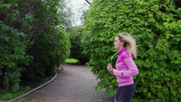 Fit Girl Runs Along City Park