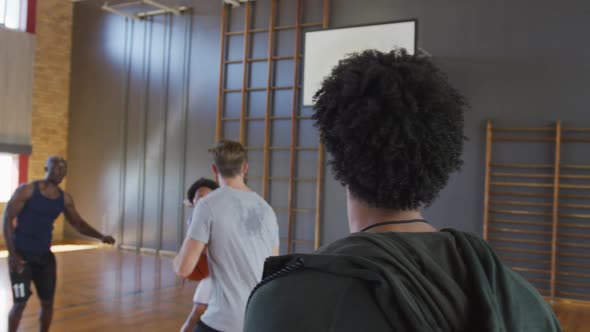 Diverse male basketball team and coach playing match