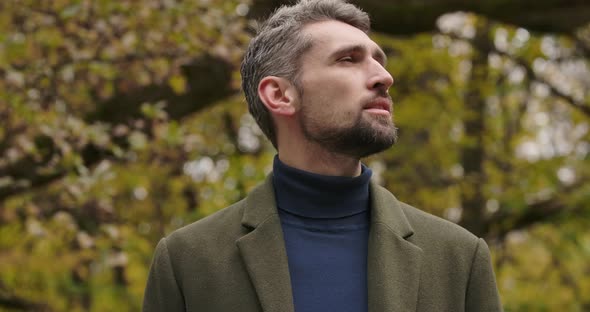 Portrait of Handsome Bearded Caucasian Man Standing in the Forest and Looking Up and Around