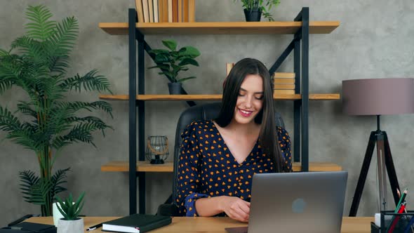 Businesswoman in home office puts on wireless earphones connects to online video call webcam laptop