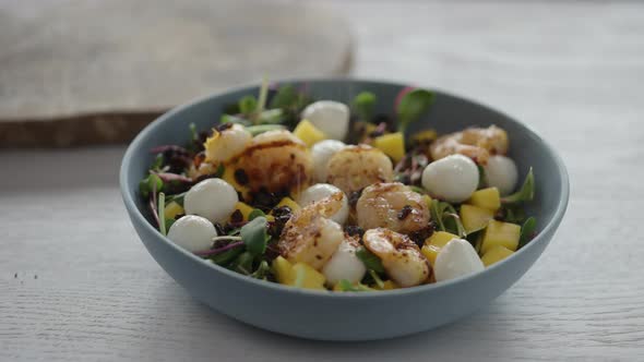 Man Seasoning Salad with Shrimps Mango Mozzarella and Micro Greens