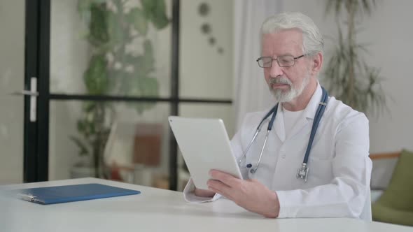 Attractive Senior Old Doctor Using Tablet in Clinic